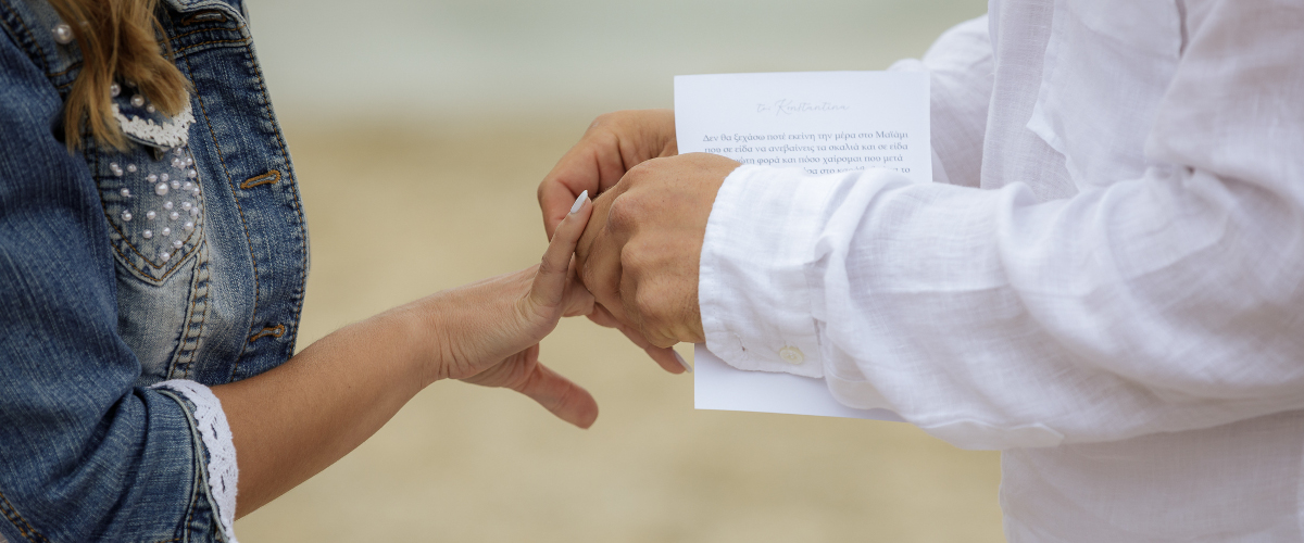 groom placing a ring on brides finger on a wedding ceremony at the beach at a destination wedding in Mykonos
