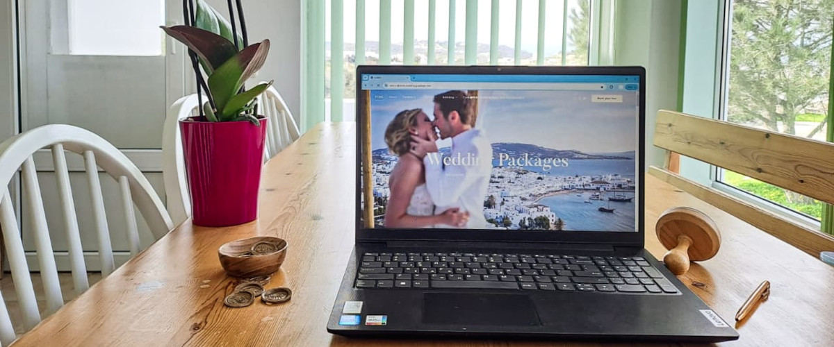 A laptop on a table beside a vase of flowers, symbolizing Mykonos wedding coordination and planning.