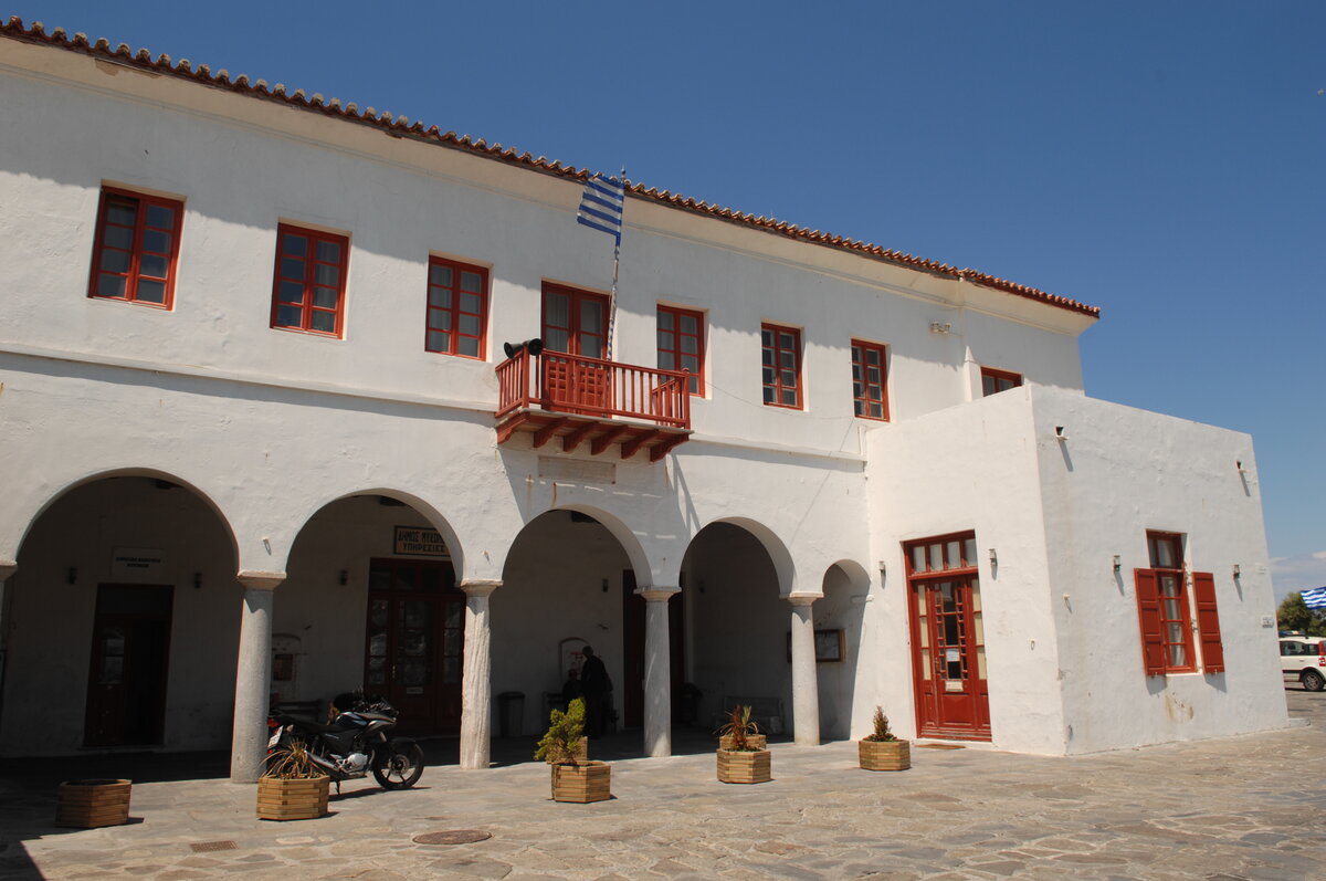 a white building with tilled roof depicting the Town hall of Mykonos where civil weddings take place