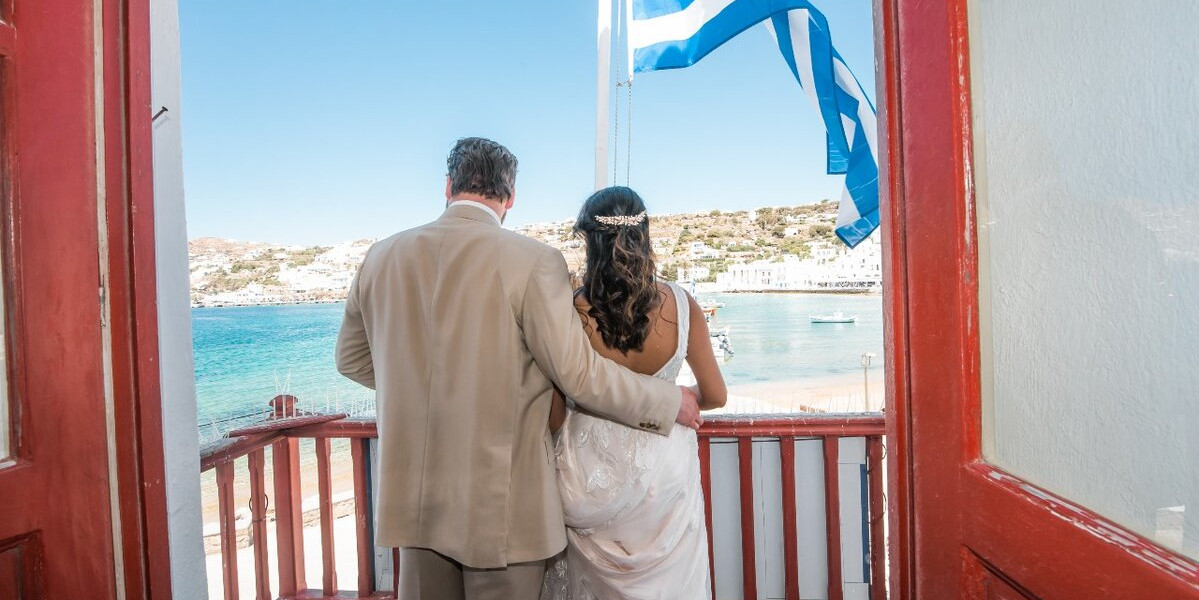 newlywed couple gazing outside the window of Mykonos town hall after their civiel weddingpackage in Mykonos